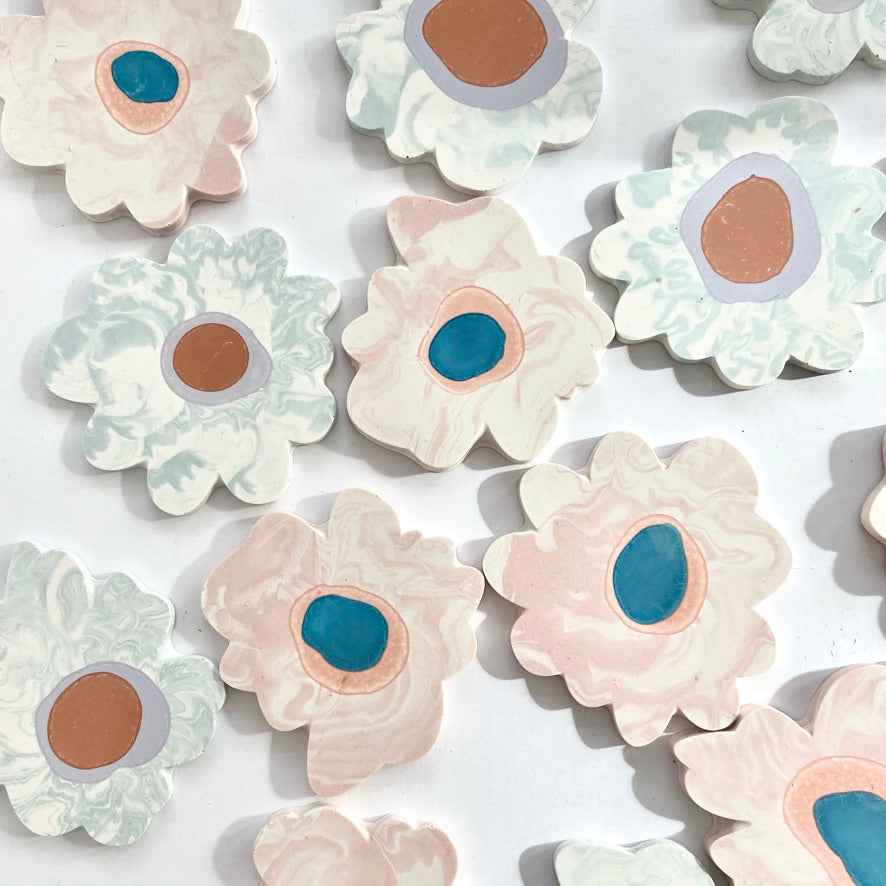 A variety of marbled Jesmonite flower-shaped coasters made with custom molds