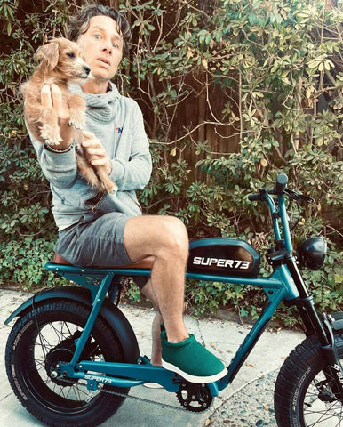 Photo of Zach Braff on his SUPER73-S2 ebike holding a puppy.