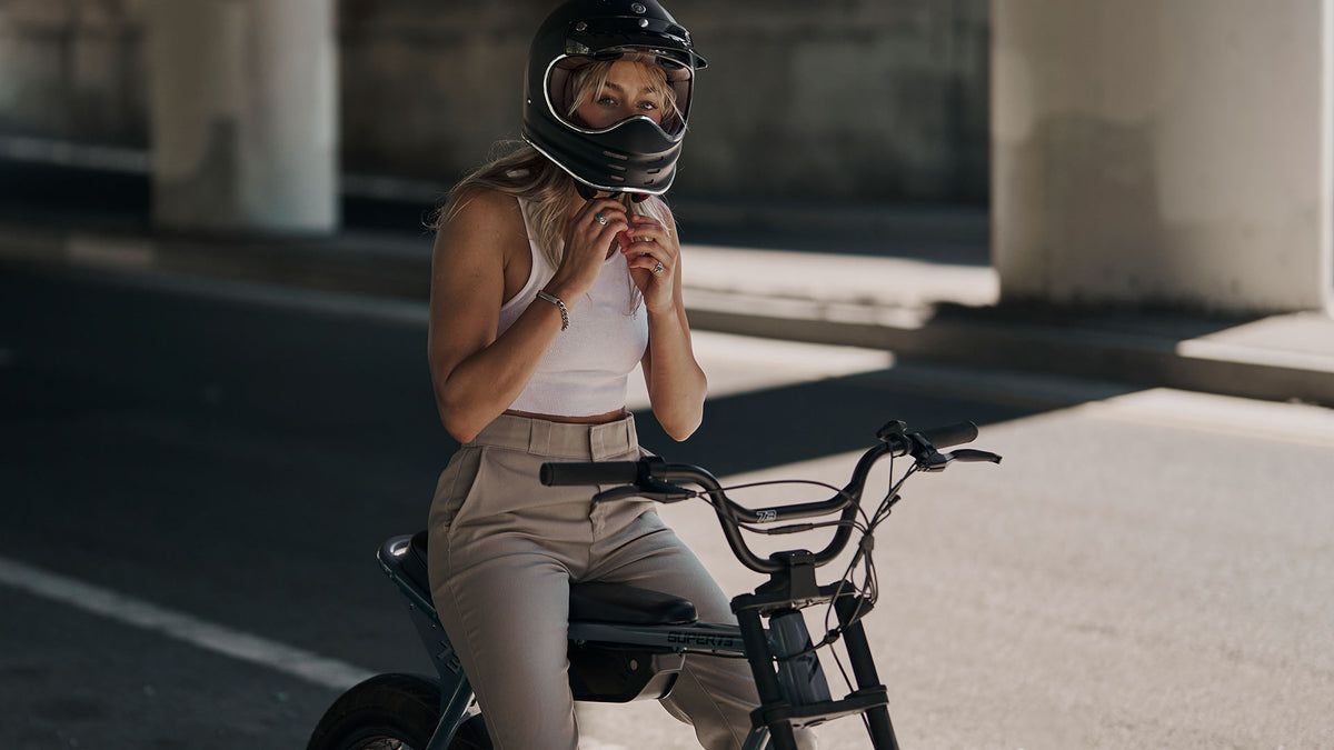 Rider tightening a helmet while sitting on a Super73 ebike that features the Blaine handlebar