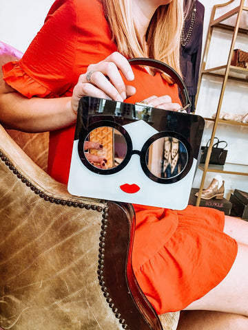 women holding handbag with women's face on it from top handle