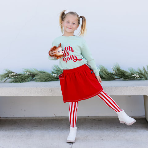 little girl in holiday outfit and pink/red vertical stripe tights