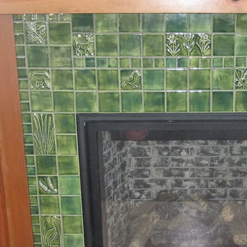 close up of green handmade tiles installed around a fireplace