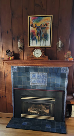 a fireplace featuring blue handmade tiles depicting the wildlife of montana