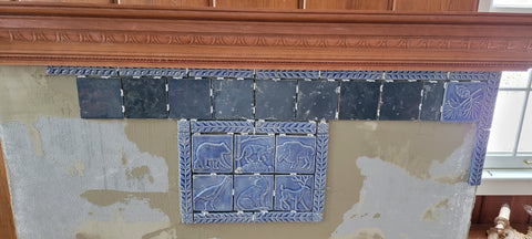 a fireplace that is being tiled with blue handmade tiles depicting the wildlife of montana