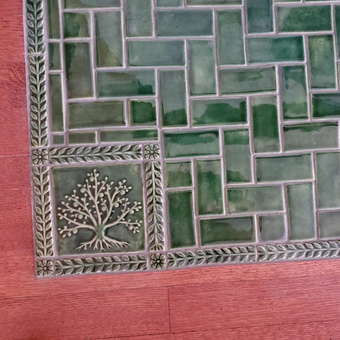 leaf green handmade tree of life tile installed with green border and field tiles in front of a victorian fireplace