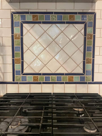 multicolored handmade tiles installed behind a cooktop in a kitchen