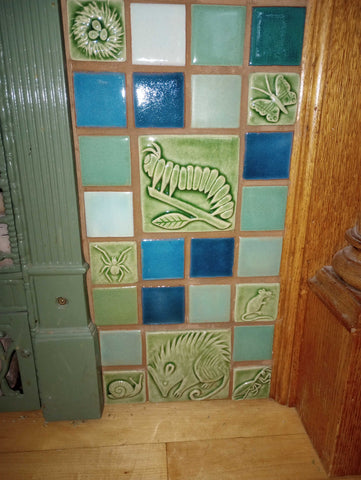 close up of handmade tile hearth featuring plant and animal designs