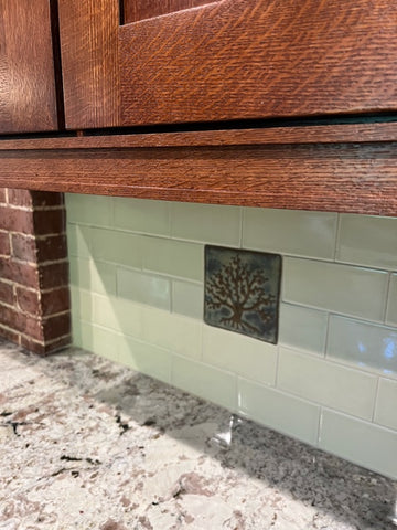 close up of a tree of life handmade tile installed in a kitchen backsplash