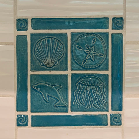 close up detail of a small, blue handmade tile mural depicting sea life and waves