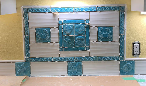 blue sea life tiles installed over a kitchen range before grout has been added