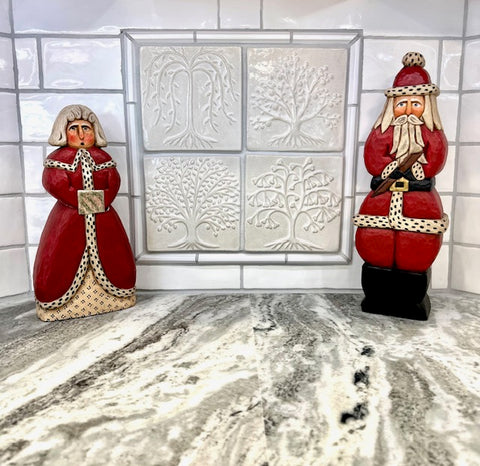 handmade creramic tree tiles, glazed in white, installed as a kitchen backsplash, with santa and mrs claus dolls displayed in front