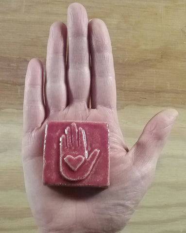 heart in hand handmade tile in the palm of a hand, red glaze