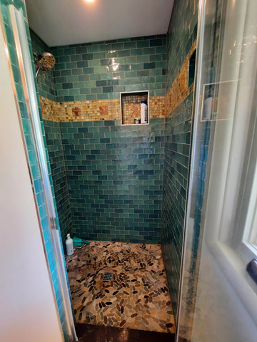 handmade tiles installed in a shower along with green subway tiles