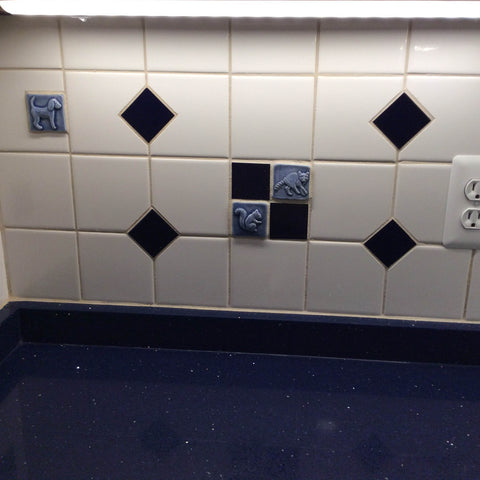 blue handmade animal tiles installed in a kitchen backsplash, close up