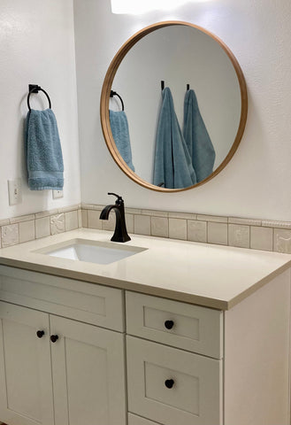 a white bathroom with handmade tiles above the sink