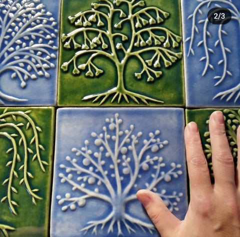 handmade blue and green tree tiles with hand for size reference