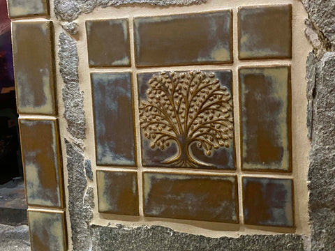 elm tree handmade tile installed with stone in a fireplace surround