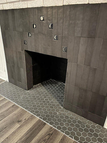 handmade moon phase tiles installed in a hearth surrounded by black subway tiles