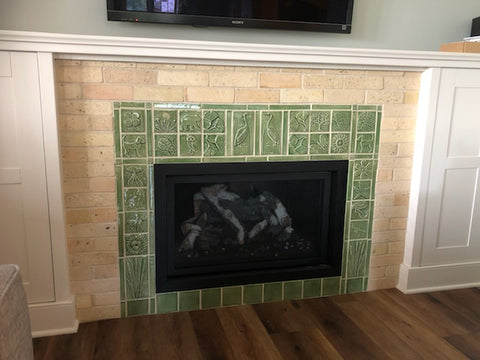 green handmade tile hearth surround featuring plants and animals