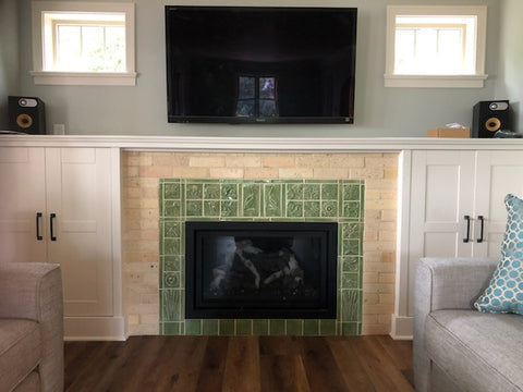 green handmade tile fireplace surround depicting plants and animals