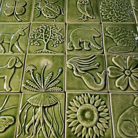 light green handmade tiles depicting plants and animals