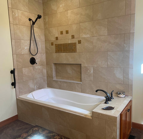 golden handmade tiles installed among commercial tiles above a shower niche