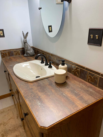 mottled brown counter and handmade tiles around a bathroom sink