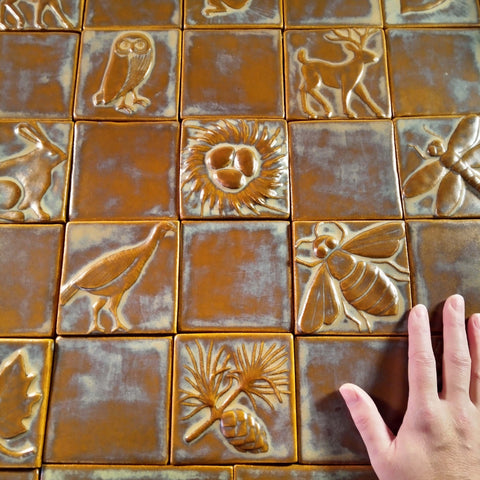 handmade tiles in brown glaze depicting plants and animals