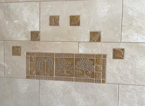 a grouping of golden handmade tiles installed in a field of much larger, slightly mottled, mass produced tiles