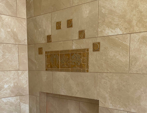 a group of golden handmade tiles set among mass produced tiles in a bathroom