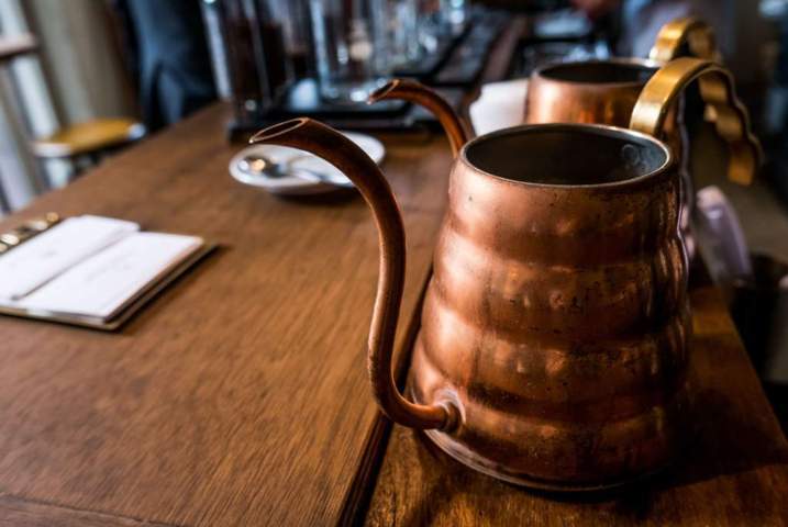 vintage copper pitchers placed on a long wooden dinning table