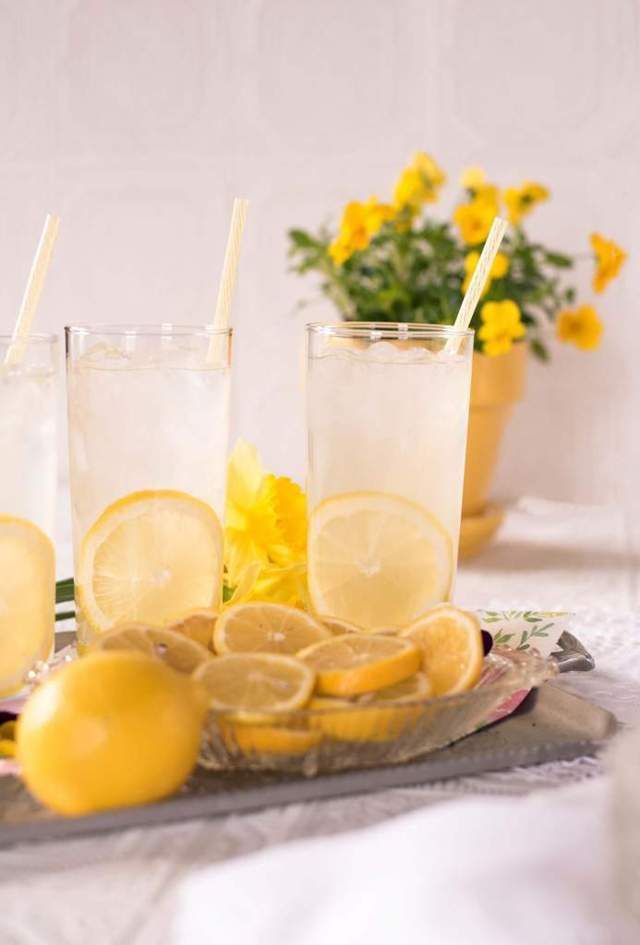 3 clear glasses filled with water and piece of sliced lemon and a straw in each