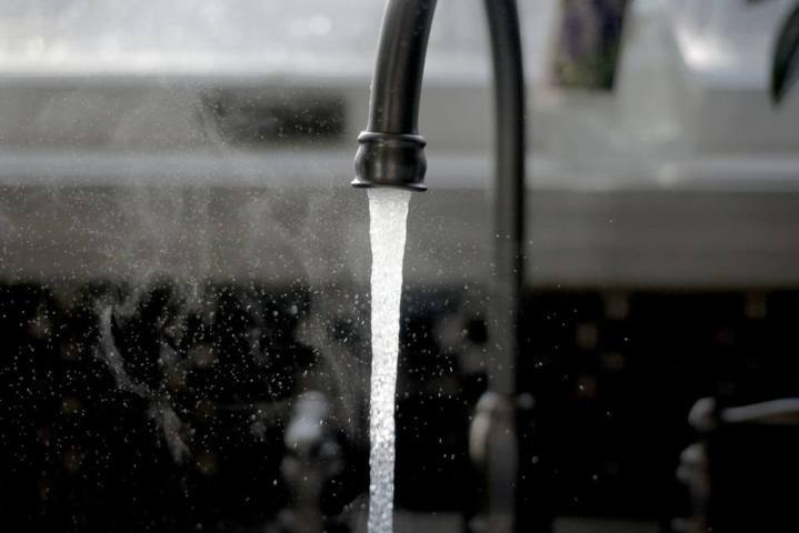 black faucet with water gushing out and spreading mist