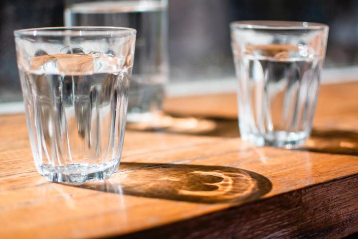 three clear drinking glass with water inside placed on top of a wooden table