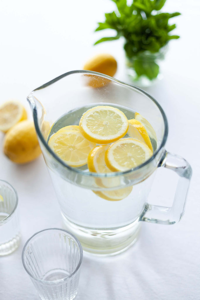 clear pitcher filled with water and pieces of sliced lemon