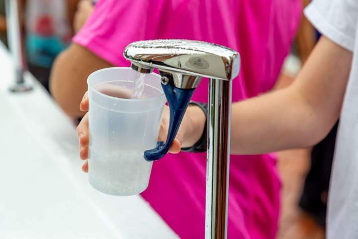 hand filling up a plastic cup with water from a faucet