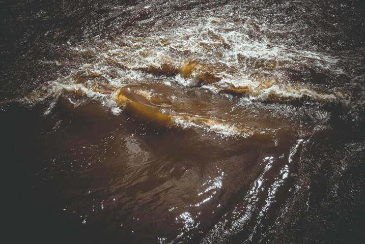 brown body of water waved forming a whirlpool