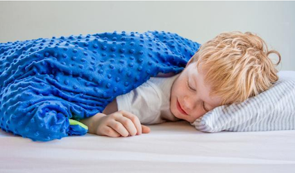 niño dormido debajo de la manta ponderada