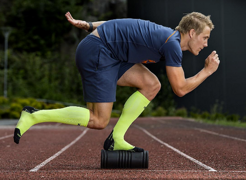 Athlete balancing on a foam roller with Zensah Compression Socks in Neon Green
