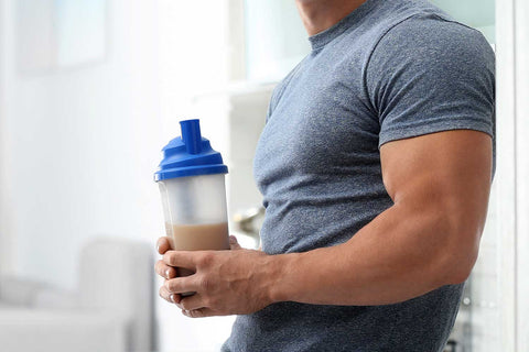 Man holding a protein shake in the kitchen