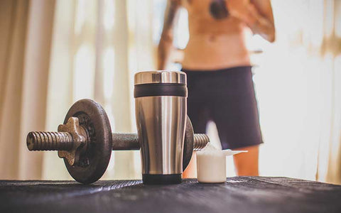 Dumbbell, shaker, and a scoop of protein powder