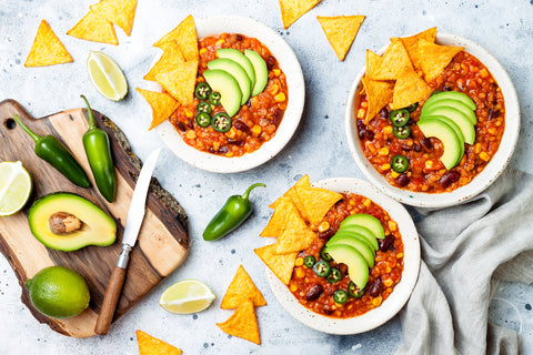 3 bowls of healthy homemade chili soup with avocado and salt-free chips on top
