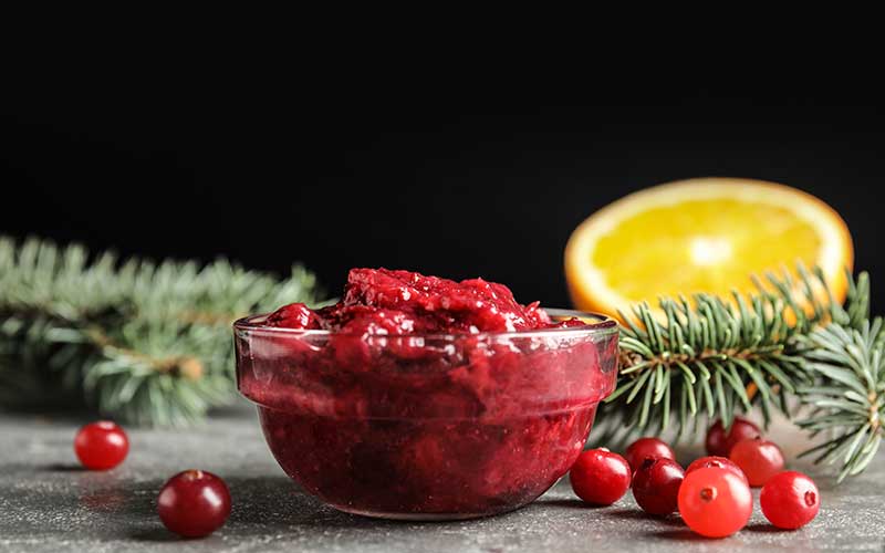 Glass bowl containing cranberry sauce on table.