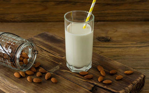 Vanilla shake in glass with almonds on wooden table.