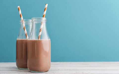 Chocolate peanut butter shake in a glass jar with two striped straws.