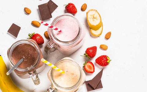 Smoothies with bananas, strawberries and chocolate on a white background.