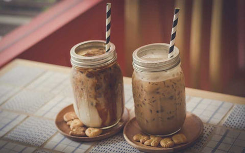 Classic iced mocha coffee protein shake in a glass jar with two striped straws.