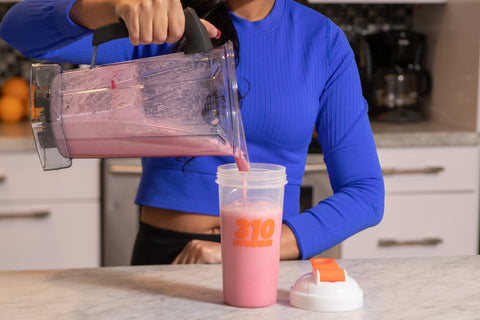 Woman pouring a meal replacement shake for weight loss into a shaker cup.