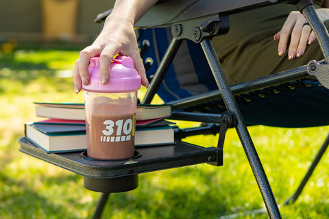 Meal replacement shake and books on a chair outside.