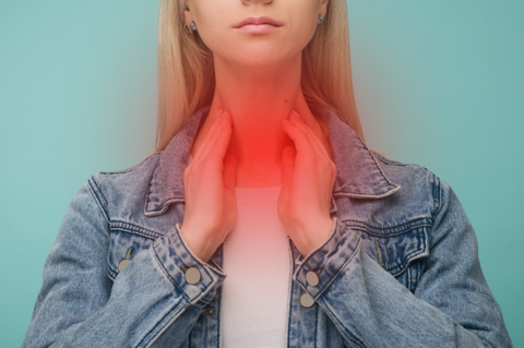 Woman experiencing thyroid pain and clutching her neck